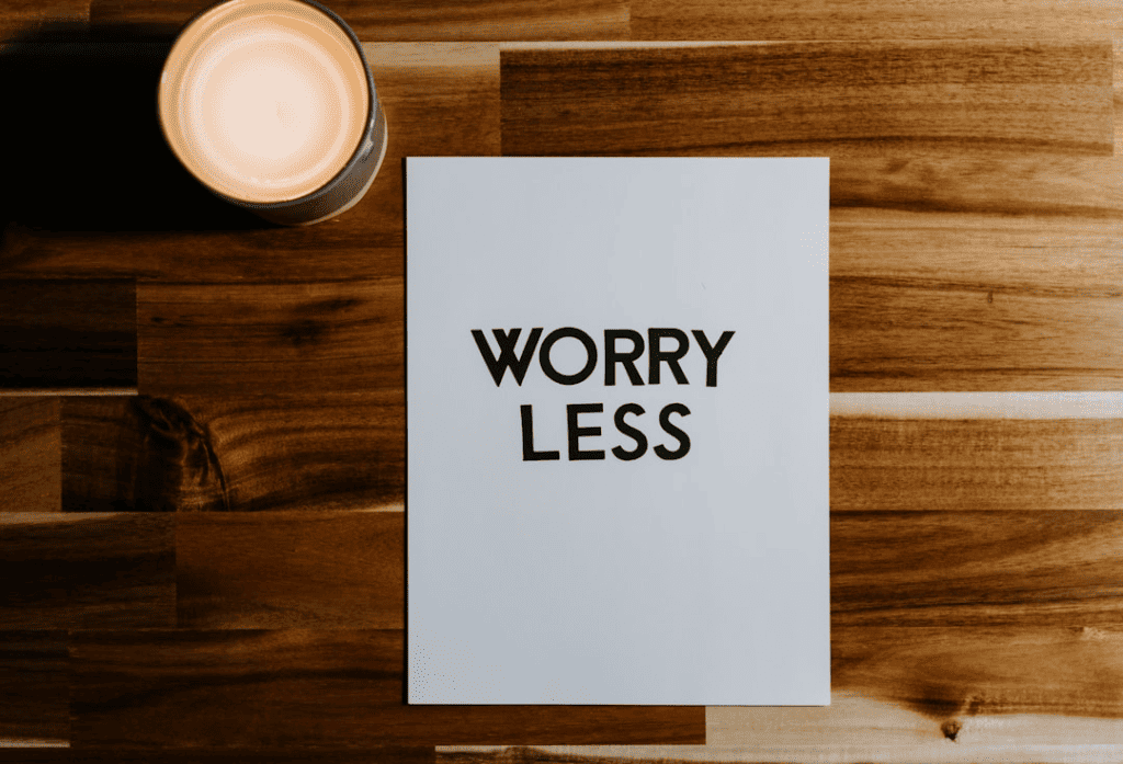 A poster having the words worry less lying on a table next to a coffee cup
