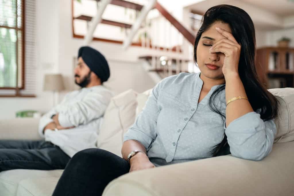 Upset young couple awaiting conflict resolution at their workplace